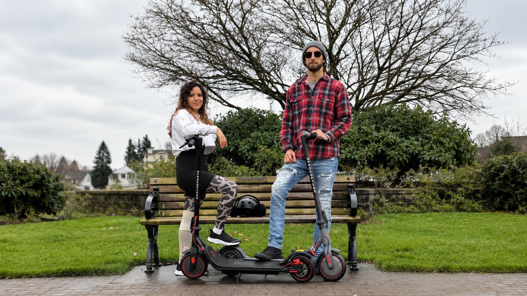 Two People standing with e-scooters in park