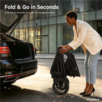 A woman in a cream blazer and light blue jeans folds a black stroller next to an open black car trunk in an urban setting. Text at the top reads 'Fold & Go in Seconds' with a small IMLoved logo in the bottom right corner.